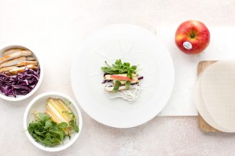 <p>Bagnate una sfoglia di riso, immergendola completamente nell’acqua per pochi secondi. Adagiatela subito sul tagliere e farcitela con il ripieno: un po’ di spaghetti di riso, di cavolo cappuccio, di rucola, di pollo, un po’ di mela e qualche fogliolina di menta.</p>
